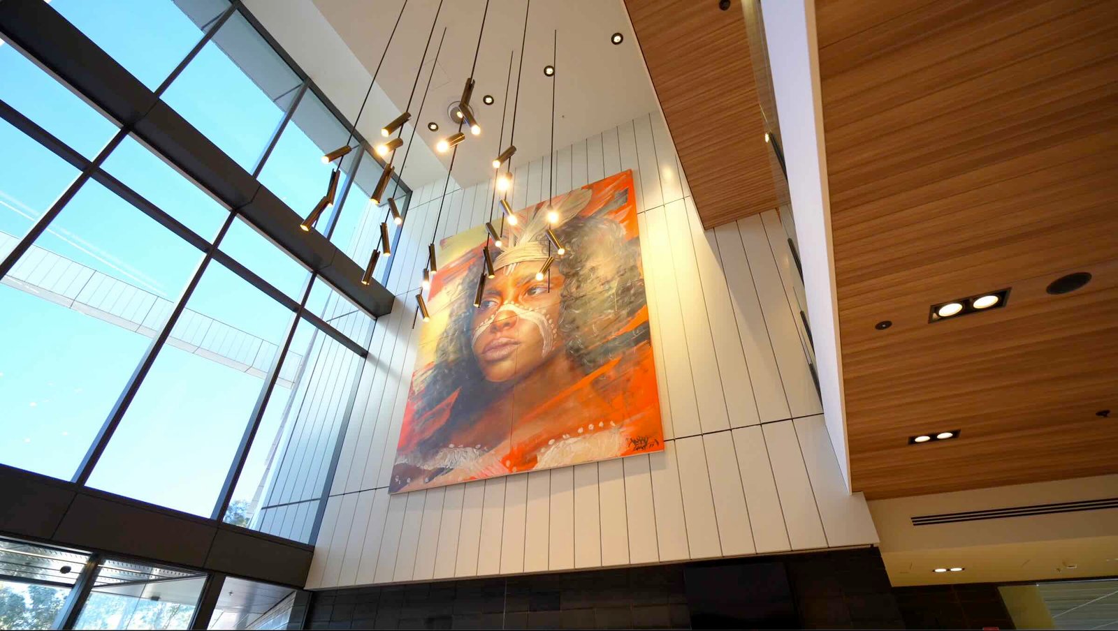 East Edge 2 foyer viewed from upper floor landing - large Indigenous artwork, blush barrel seating and glass balustrade with brass rail